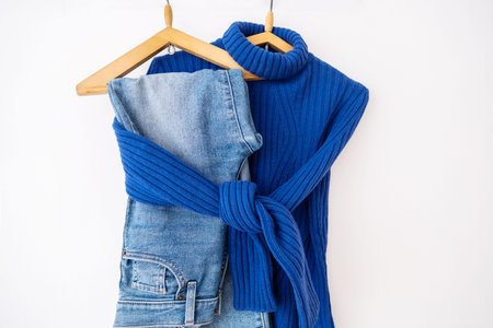 Vibrant blue knit sweater paired with denim jeans on wooden hangers