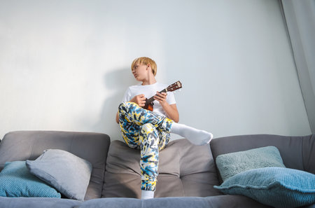 Ukulele player teen boy at home.の写真素材