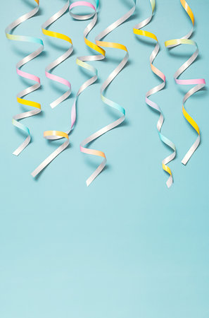 Colorful party streamers hanging down against pastel blue background.の写真素材