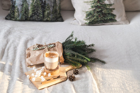 Cozy winter holiday scene with coffee cup, and pine branches on white bedspread.の写真素材