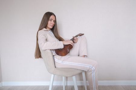 Woman with ukulele sitting on a chair.の写真素材