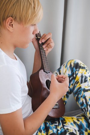 Teenage boy practicing strumming on ukulele.の写真素材