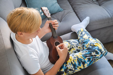Teenage boy practicing strumming on ukulele.の写真素材