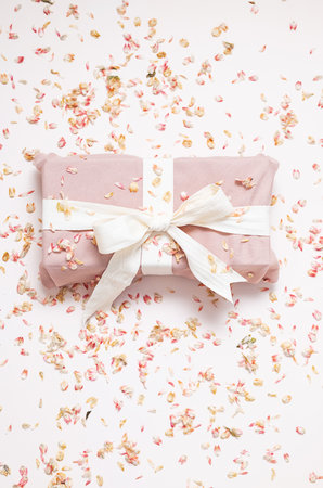 Sustainable wrapped present and dried petals confetti. Zero waste holiday background.の写真素材