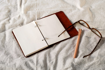 Open notebook, pen and glasses on cozy bed. Productive relaxation and creative inspiration concept.の写真素材