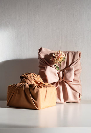 Elegant fabric wrapped gift boxes with dried flowers, styled on white table. Organic and perfect for zero waste holiday.の写真素材
