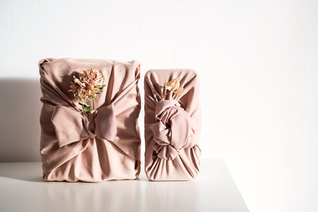 Elegant fabric wrapped gift boxes with dried flowers, styled on white table. Organic and perfect for zero waste holiday.の写真素材