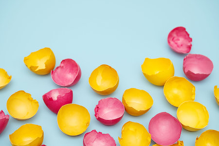 Cracked Yellow and Pink Easter Eggshells on Blue. Flat Lay with Copy Space.