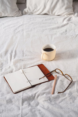 Open Journal with Pen on White Blanket, Next to Coffee Mug and Eyeglasses.