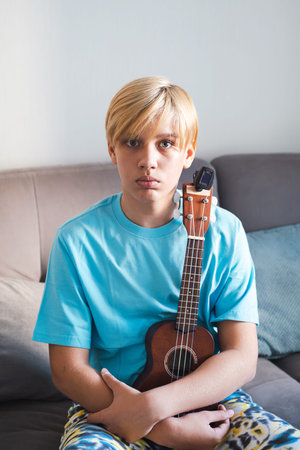Thoughtful Teenage Boy Holding Ukulele.