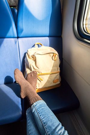 Relaxed Female Traveler with Backpack on Train Journey, Feet Resting on Seat.の写真素材