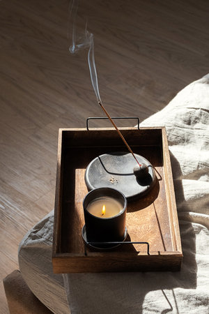 Burning Candle and Aroma Stick Incense on Wooden Tray for Calm Balance and Wellbeing.の写真素材