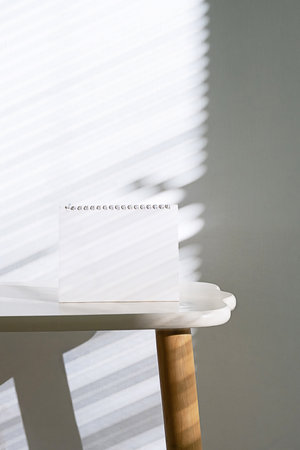 Blank Calendar on the Table with Light from Blinds. Modern Template Mockup for Invitations and Promotions.の写真素材