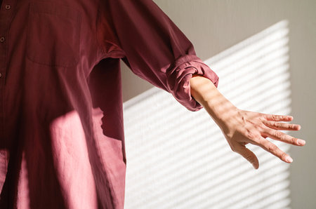 Cropped Woman in Maroon Shirt Reaching Out. Creative Mood for Blog, Fashion or Magazine.の写真素材