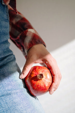 Woman Holds Ripe Pomegranate Fruit in Hand for Healthy Eating, Snack Preparation or Ingredient in...