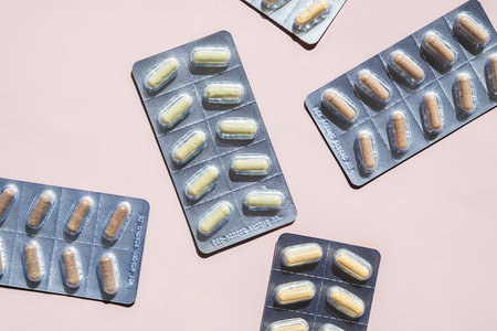 Multiple Blister Packs Filled with Translucent Drug Dose Capsule on Pink Background. Medication,...