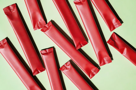 Red Stick Packs Scattered on Green. Beverage Packaging Mockups and Food Product Presentation.の写真素材