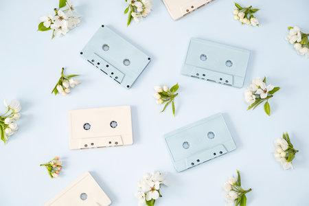 Audio Cassette Tapes Arranged with White Flowers on Blue Background. Vintage Music and Spring Floral Concept.の写真素材