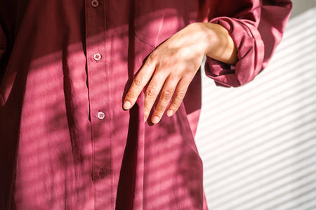Woman Showing the Texture of Red Fabric Clothing. Sunlight and Shadows on Textured Cotton Garment.の写真素材