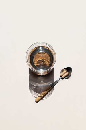 Illuminating Glass of Water and Spoon with Two Pills on Light Background, Promoting Healthy Lifestyle.の写真素材