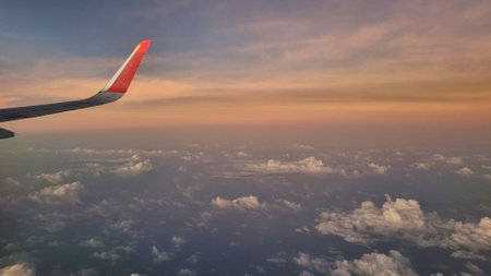 View From Airplane Window of Wing During Sunset. Sky Above Clouds with Vibrant Colors.の写真素材