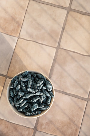 Bowl Full of Honeysuckle Berry on Tile Surface. Healthy Eating and Delicious Snack.の写真素材