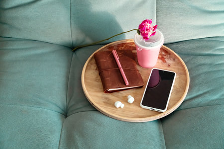 Wooden Tray with Notebook, Pen, Smartphone and Drink on Sofa. Relaxing Leisure with Digital Media at Home.の写真素材