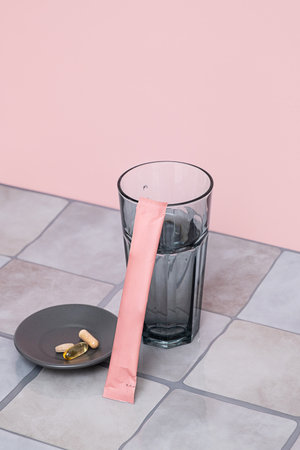 Nutritional supplement powder packet with glass of water and natural medicine pills for health and beauty.の写真素材