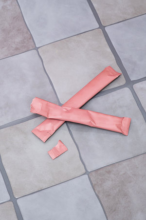 Two pink individual sample packets of sweetener or powder, one opened. Product display.の写真素材