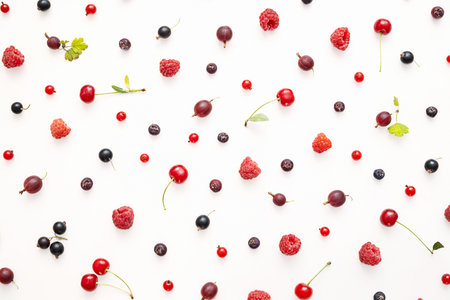 Assortment of fresh colorful berries scattered on white background. Healthy eating and summer fruit concept for seasonal design.の写真素材
