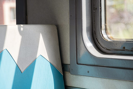 Sunlight streaming onto an empty train seat and window, showing light and shadow for local trip.