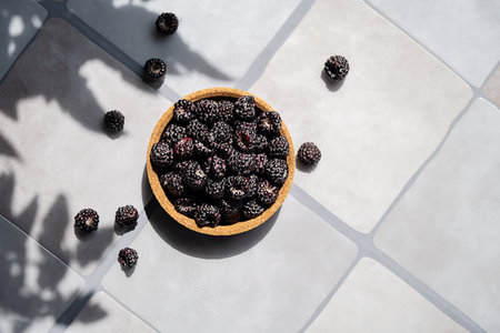 Bowl of black raspberries on tile surface. Superfood concept for health and nutrition. Vegan foodの写真素材