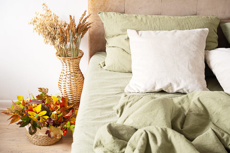 Cozy bedroom interior with green linen bedding and autumn decoration. Warm fall home style for comfort and relaxation.の写真素材