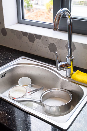 Kitchen sink filled with dirty dishes. Housework and cleaning concept for household chore. Untidy...
