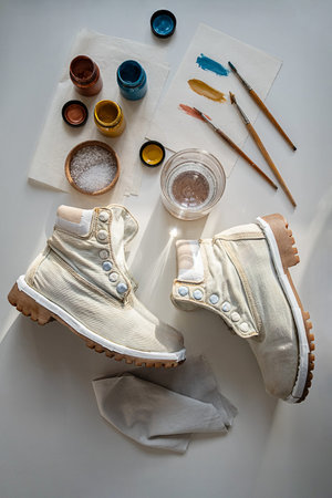 Plain canvas boots ready for repainting. Preparing shoes for customization with paint pots and...