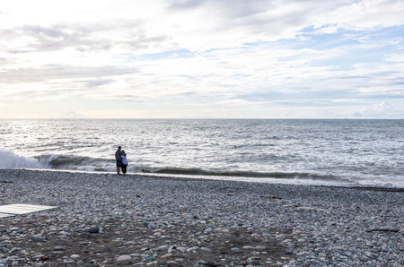 Couple in love on a pebble beach admiring the seaの写真素材