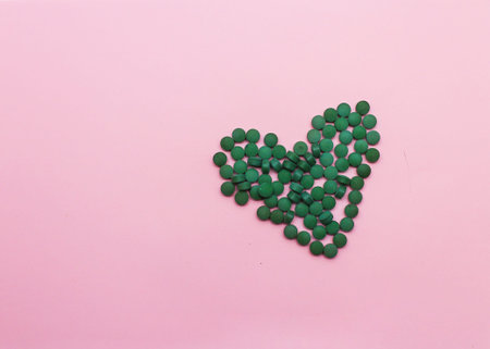 pills laid out in the shape of a heart on a pink backgroundの写真素材