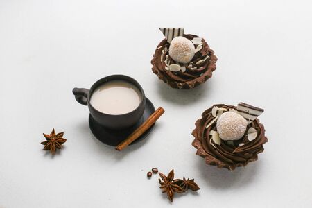 Two chocolate brownies with coconut and a brown cup with milk on a white backgroundの写真素材