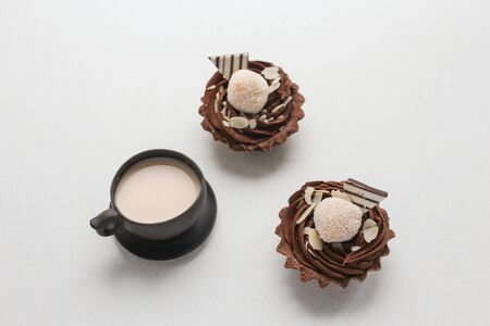 Two chocolate brownies with coconut and a brown cup with milk on a white backgroundの写真素材