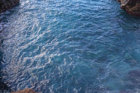 Ocean waves crashing onto the rocks in the sunset. Blue azure waterの写真素材