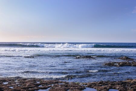 Ocean waves crashing onto the rocks in the sunset. Blue azure waterの写真素材