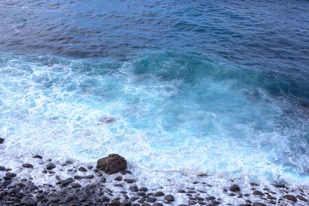 Ocean waves crashing onto the rocks in the sunset. Blue azure waterの写真素材
