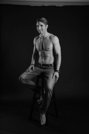 black and white studio shoot of strong athletic man on dark background. sexy bodyの写真素材