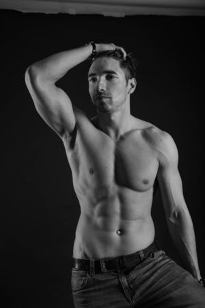 black and white studio shoot of strong athletic man on dark background. sexy bodyの写真素材