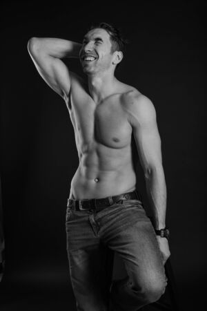 black and white studio shoot of strong athletic man on dark background. sexy bodyの写真素材