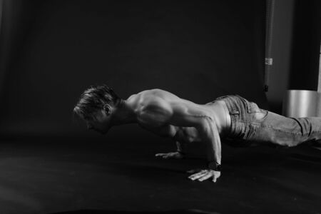 Muscular man doing push-ups on one hand against dark background. sexy bodyの写真素材