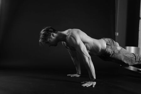 Muscular man doing push-ups on one hand against dark background. sexy bodyの写真素材