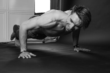 Muscular man doing push-ups on one hand against dark background. sexy bodyの写真素材