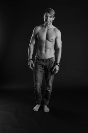 black and white studio shoot of strong athletic man on dark background. sexy bodyの写真素材