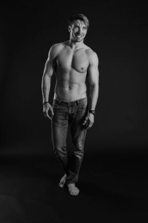 black and white studio shoot of strong athletic man on dark background. sexy bodyの写真素材